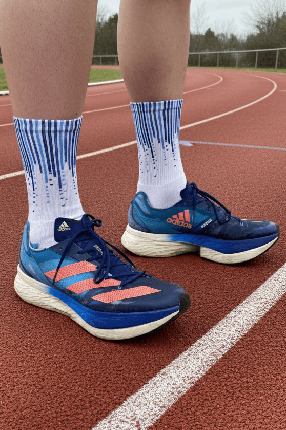 Person wearing blue running shoes with orange accents on a track