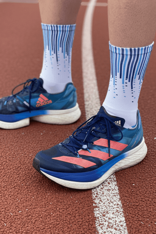 Person wearing blue running shoes with red accents on a track