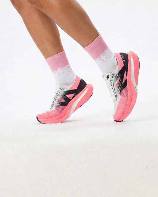 Pink and black athletic shoes worn with white socks on a light gray background