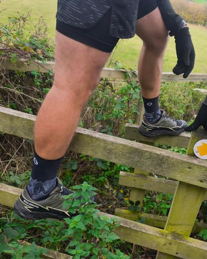 Two people climbing a wooden fence in a natural setting