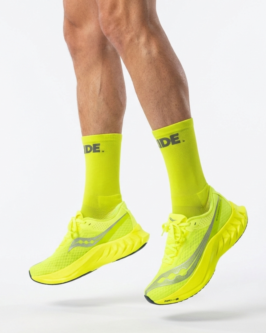 Bright yellow running shoes and socks with 'RIDE' branding on a white background