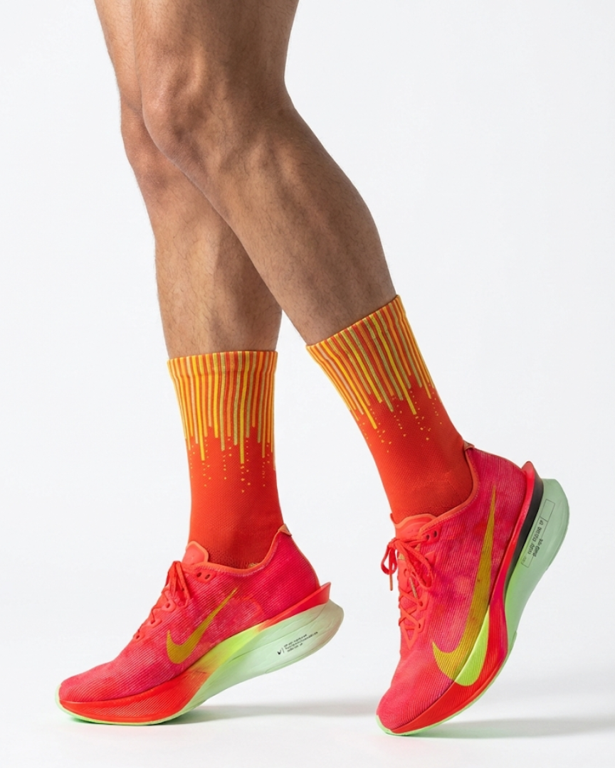 Person wearing bright orange running shoes and socks on a light gray background