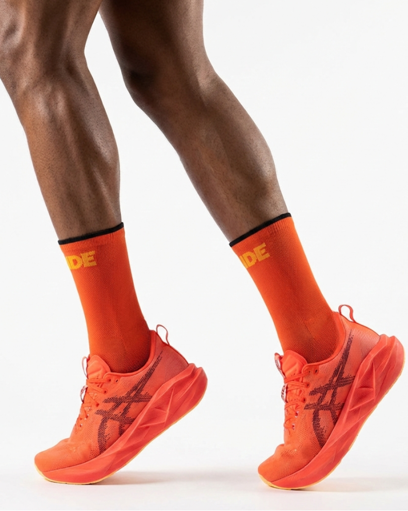 Orange running shoes and socks with a brand logo on a white background