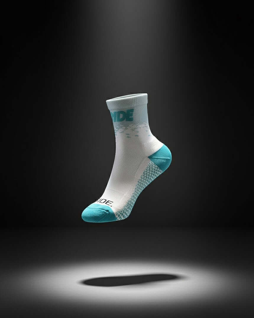 White and turquoise cycling sock on a dark background, spotlighted from above.