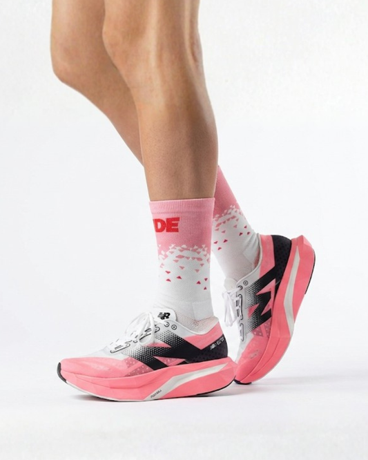 Person wearing pink and black running shoes with visible brand logo on a white background