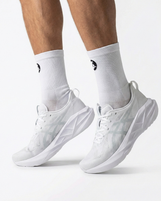 White sneakers worn with white socks on a light gray background