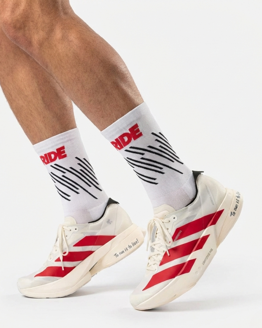 White socks with red and black text and stripes worn with red and white sneakers on a white background